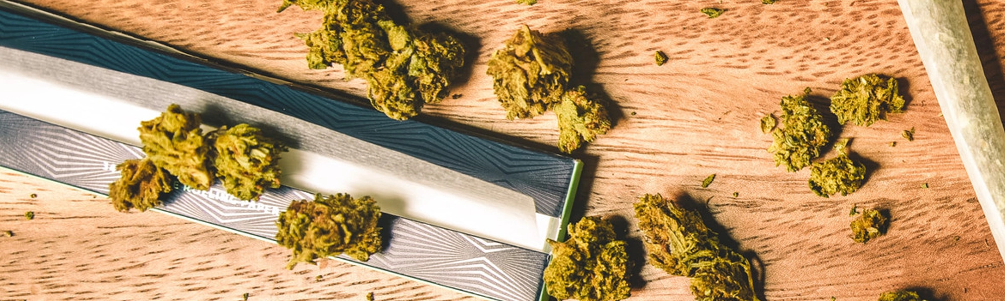Step-by-step use of a cannabis rolling machine showing ground flower and rolling paper in the device